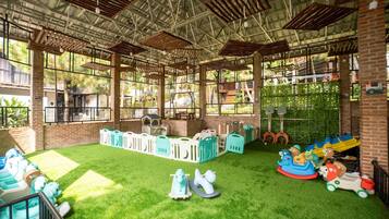 An indoor play area with artificial grass, play structures, and a brick wall.