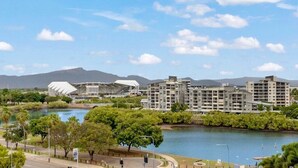 A riverside view with modern buildings, a stadium, and a park. - Studio Escape | Views, Dining, Stadium & CBD (South Townsville)