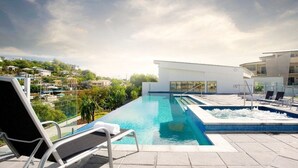 A rooftop infinity pool with lounge chairs, a hot tub, and a view of the city. - Studio Escape | Views, Dining, Stadium & CBD (South Townsville)