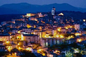 A densely packed hillside town with buildings illuminated at night. - Suite Vallombrosa - Premium Apartment Near the Fonti of Fiuggi (Fiuggi)