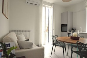 A modern living room with a sofa, dining table, chairs, and a kitchen area with appliances. - Suite Vallombrosa - Premium Apartment Near the Fonti of Fiuggi (Fiuggi)