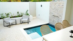 A pool area with a white wall, a brick wall, and a white fence. There are two white chairs and two wicker chairs. - Walk to Beach New Elegant 3BR with Pool  (Lower Carlton)