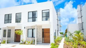 A modern two-story building with a white facade, large windows, and a wooden door. - Walk to Beach New Elegant 3BR with Pool  (Lower Carlton)