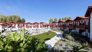 Ein Hotel mit mehreren Gebäuden mit roten Dächern, einem Schwimmbad und einem gepflegten Rasen.