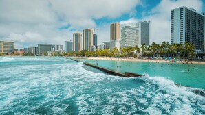 A coastal cityscape with high-rise buildings, a beach, and a pier extending into the ocean. - Sans Souci Shoreline Gold Coast Lodging 30+ Day (Honolulu)