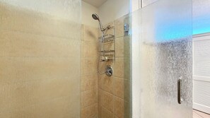 Ein Badezimmer mit Dusche, gefliesten Wänden und einer Tür mit Griff.
