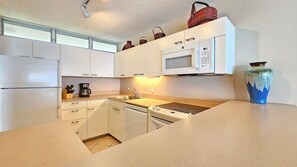 Eine moderne Küche mit weißen Schränken, einer eingebauten Mikrowelle, einer Kaffeemaschine und einer Vase auf der Arbeitsplatte.