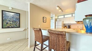 A modern kitchen with white cabinets, a coffee maker, and a blue vase. - Sans Souci Shoreline Gold Coast Lodging 30+ Day (Honolulu)