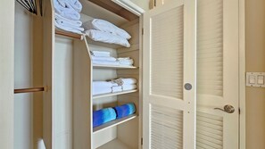 A hotel room with a walk-in closet containing neatly folded towels and a blue towel on the bottom shelf. - Sans Souci Shoreline Gold Coast Lodging 30+ Day (Honolulu)
