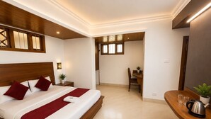 A modern hotel room with a large bed, a desk, and a chair. - Gangtok Central Rooms (Gangtok)