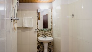 A bathroom with a white sink, a mirror, and a shower area. - Gangtok Central Rooms (Gangtok)