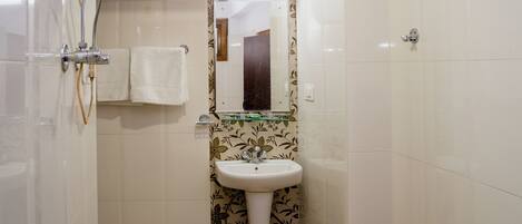 A bathroom with a white sink, a mirror, and a shower area.