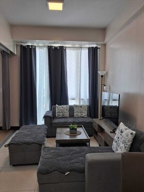 A modern living room with a sofa set, a coffee table, and a television. - Mactan Infinity Pool View Near Airport & Beach (Lapu-Lapu)