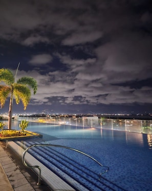 A nighttime pool area with palm trees, a clear sky, and a cityscape in the background. - Mactan Infinity Pool View Near Airport & Beach (Lapu-Lapu)