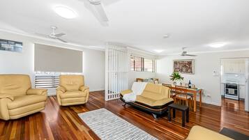 A living room with two sofas, a dining table, and a kitchen area.