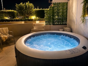 A hot tub with a control panel, surrounded by a patio area with steps and a chair. - Beachfront Jacuzzi Retreat Seaview Walk Everywhere (Saronida)
