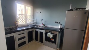 Een keuken met een gasfornuis, spoelbak, oven en een koelkast.