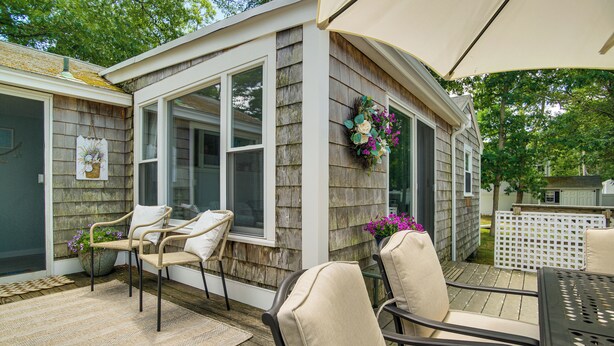Un patio cubierto con mobiliario exterior, una ventana con vistas y un adorno decorativo.