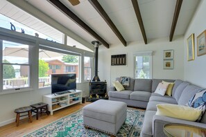 Ein Wohnzimmer mit Kamin, Sofa, Hocker und Fernseher.
