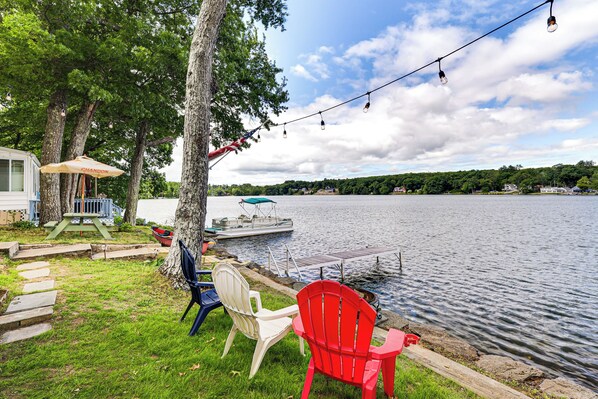 A lakeside setting with a dock, chairs, and a boat. - Dock & Sunset Views! Waterfront Thompson Getaway (Thompson)
