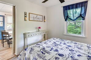 A bedroom with a bed, a desk, a chair, a window with curtains, and a wall with a framed sign. - Dock & Sunset Views! Waterfront Thompson Getaway (Thompson)