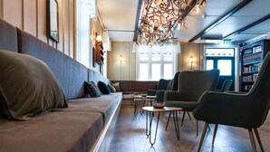 Un área de descanso moderna con sofá, sillones, una mesita de centro y una estantería.