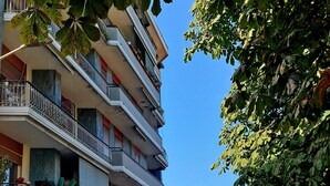 Un immeuble à plusieurs étages doté de balcons, une rue devant et des voitures garées.