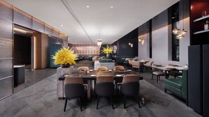 Uma zona de refeições moderna com uma mesa comprida, cadeiras e iluminação pendente.