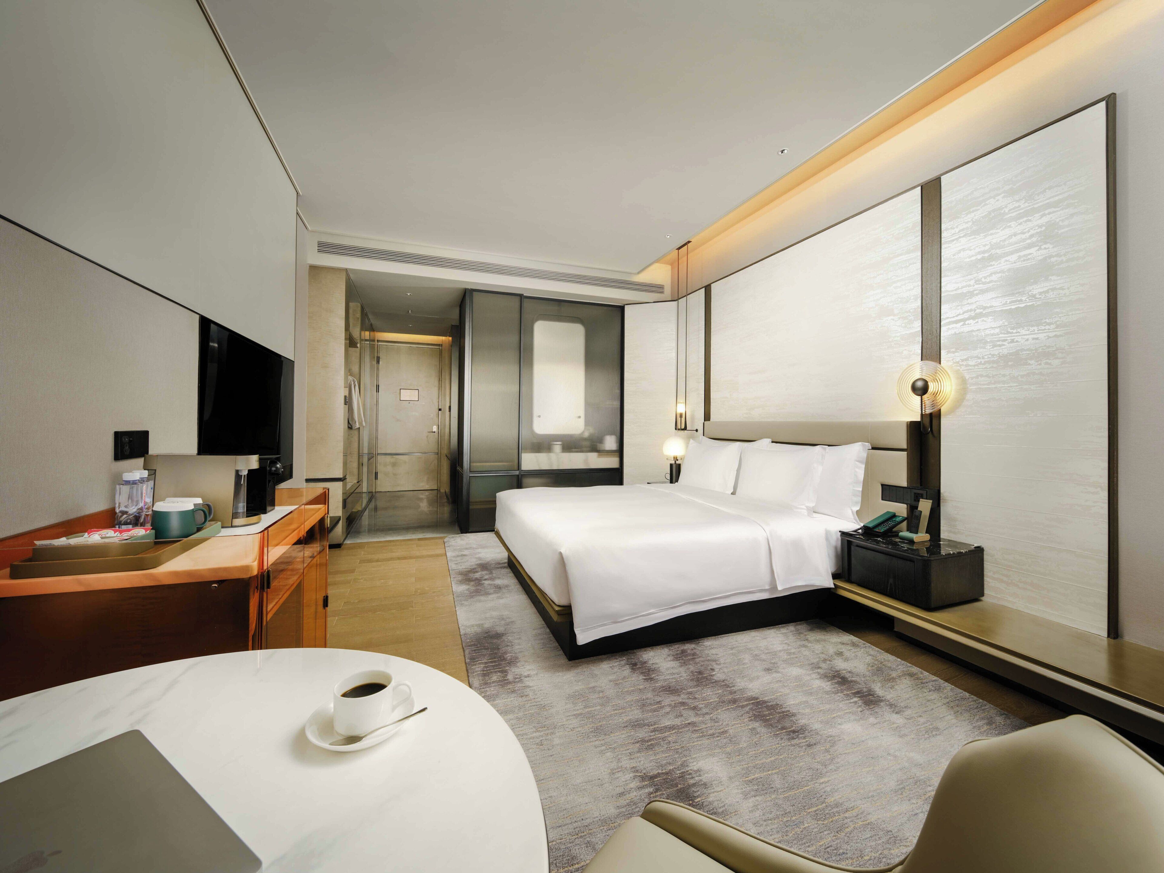 Una habitación de hotel con cama, mesita de noche, lámpara y escritorio con silla.
