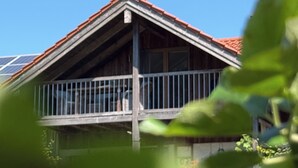 Ein Haus mit einem geneigten Dach, einem Balkon mit Metallgeländern und Solaranlagen auf dem Dach.