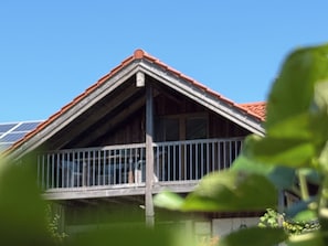Ein Haus mit einem geneigten Dach, einem Balkon mit Metallgeländern und Solaranlagen auf dem Dach.