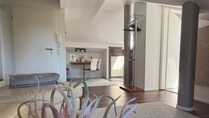 Ein modernes Interieur mit einer Couch, einer Pflanze, einem Essbereich und einem großen Fenster.