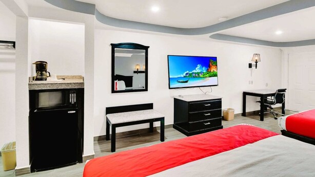 Habitació d'hotel amb llit, escriptori, cadira, televisió, microones, petita armariació i finestra.