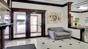 A lobby with a grey sofa, a clock on the wall, and a reception desk. - King Bed Non Smoking (Three Rivers TX)