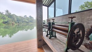 Una habitación con un amplio ventanal que da a un cuerpo de agua tranquilo y abundante vegetación.