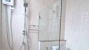 Un baño con cabina de ducha de vidrio, inodoro y calentador de agua.