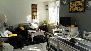 Ein Wohnzimmer mit Sofa, Couchtisch, Fernseher und Essbereich.