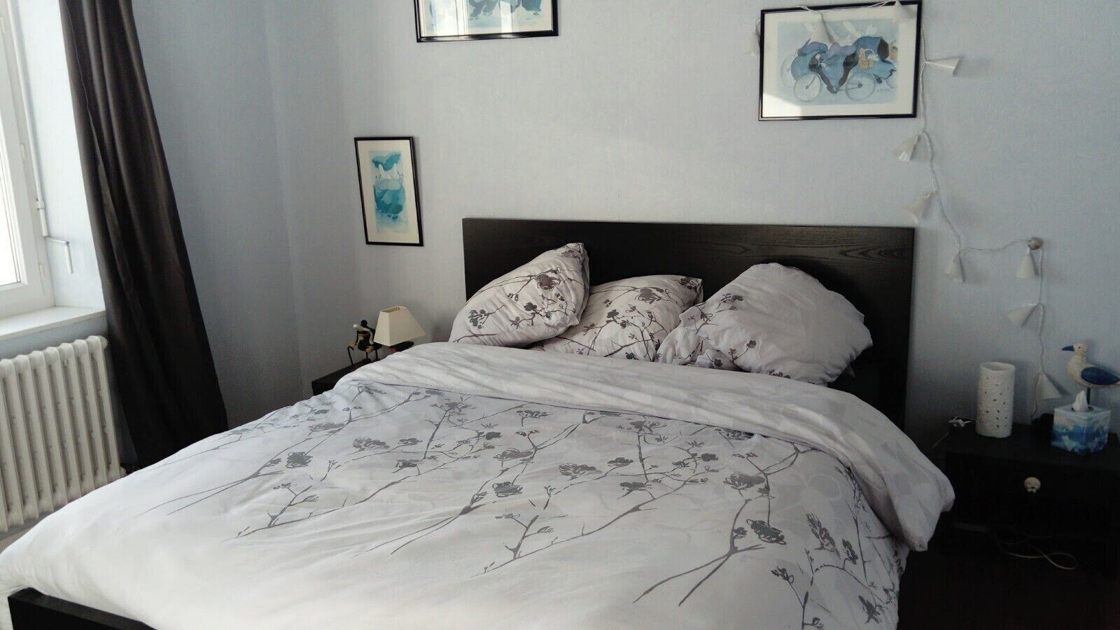 A bedroom with a bed, a nightstand, a lamp, and wall art.