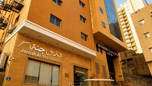 Un hotel con un cartel en árabe e inglés, un símbolo de accesibilidad para sillas de ruedas y una escalera que sube a un nivel superior.