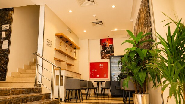 Vestíbulo de hotel con escaleras de mármol, una recepción, zona de estar y una gran planta en maceta.