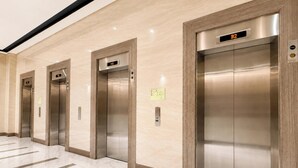 Vários elevadores em linha, com mostradores digitais exibindo os números dos andares.