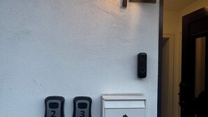 Un système d’interphone mural, des sonnettes numérotées et une fente pour le courrier.