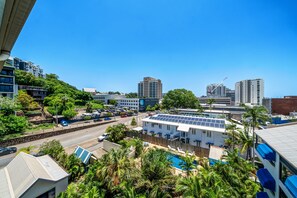 A residential area with a swimming pool, solar panels, and a view of the cityscape. - Top-Floor City Apartment with Stadium & Mountain Views (Townsville)