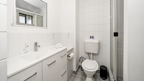 Kylpyhuone, jossa on valkoinen pesuallas, peili, wc ja suihku.