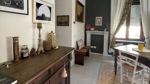Een eetgedeelte met een houten tafel en stoelen, een open haard en diverse wanddecoraties.