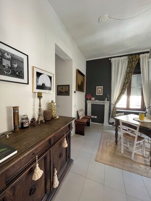 A dining area with a wooden table and chairs, a fireplace, and various wall decorations. - Charming apartment near Assisi (Santa Maria degli Angeli)