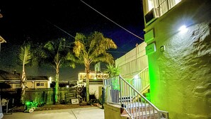 A nighttime view of a residential area with a house featuring a green exterior, a staircase, and a visible address number. - Beverlywood Apt Master Suite - Private Bath & Production Studio (Los Angeles)
