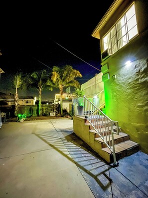 A nighttime view of a residential area with a house featuring a green exterior, a staircase, and a visible address number. - Beverlywood Apt Master Suite - Private Bath & Production Studio (Los Angeles)