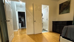 A room with wooden flooring, a bed, a painting on the wall, and a door leading to another room. - Beverlywood Apt Master Suite - Private Bath & Production Studio (Los Angeles)