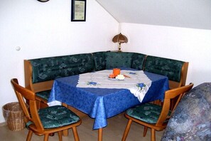 Un coin repas avec une table dressée pour quatre personnes, entourée de chaises rembourrées recouvertes d’un tissu à motifs.